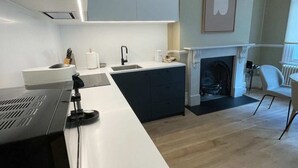 Eine moderne Küche mit weißer Arbeitsplatte, einem eingebauten Backofen und einem Kamin im Hintergrund.
