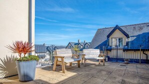 A patio with two wooden benches and a potted plant. - Minarvon - 2 Bedroom Apartment - Saundersfoot (Saundersfoot)