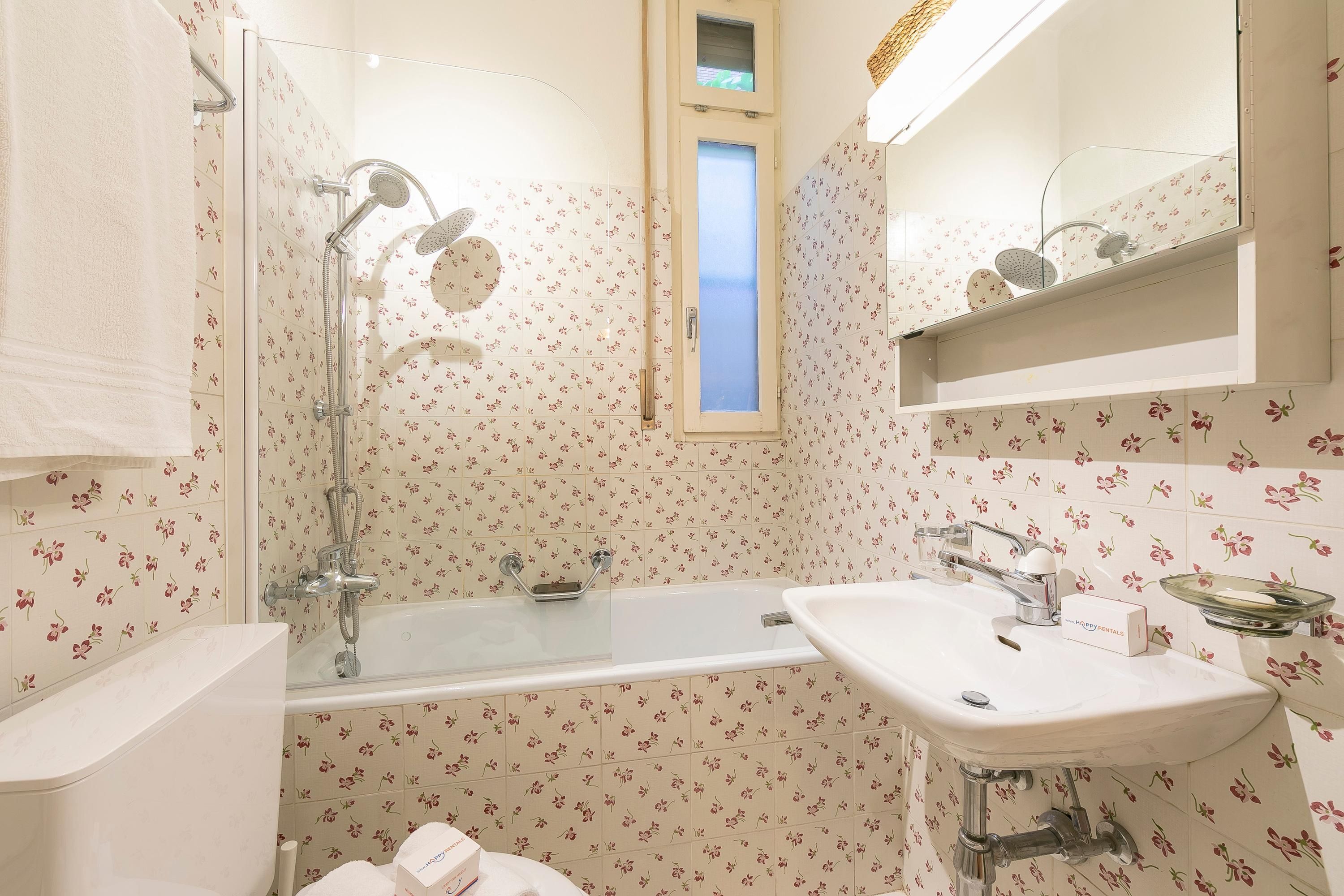 A bathroom with a glass-enclosed shower, a white sink, and a mirror above the sink.