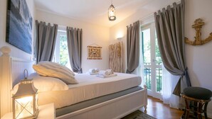A bedroom with a bed, a bedside table with a lantern, a chair, and a view of greenery outside. - Villa Victor 100m From sea (Massa)