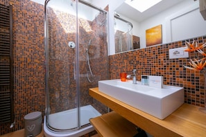 A modern bathroom with a glass shower enclosure, a white sink with a wooden countertop, and a tiled backsplash. - Villa Victor 100m From sea (Massa)