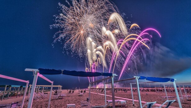 A beach with rows of sun loungers and umbrellas, and a fireworks display in the background. - Villa Victor 100m From sea (Massa)