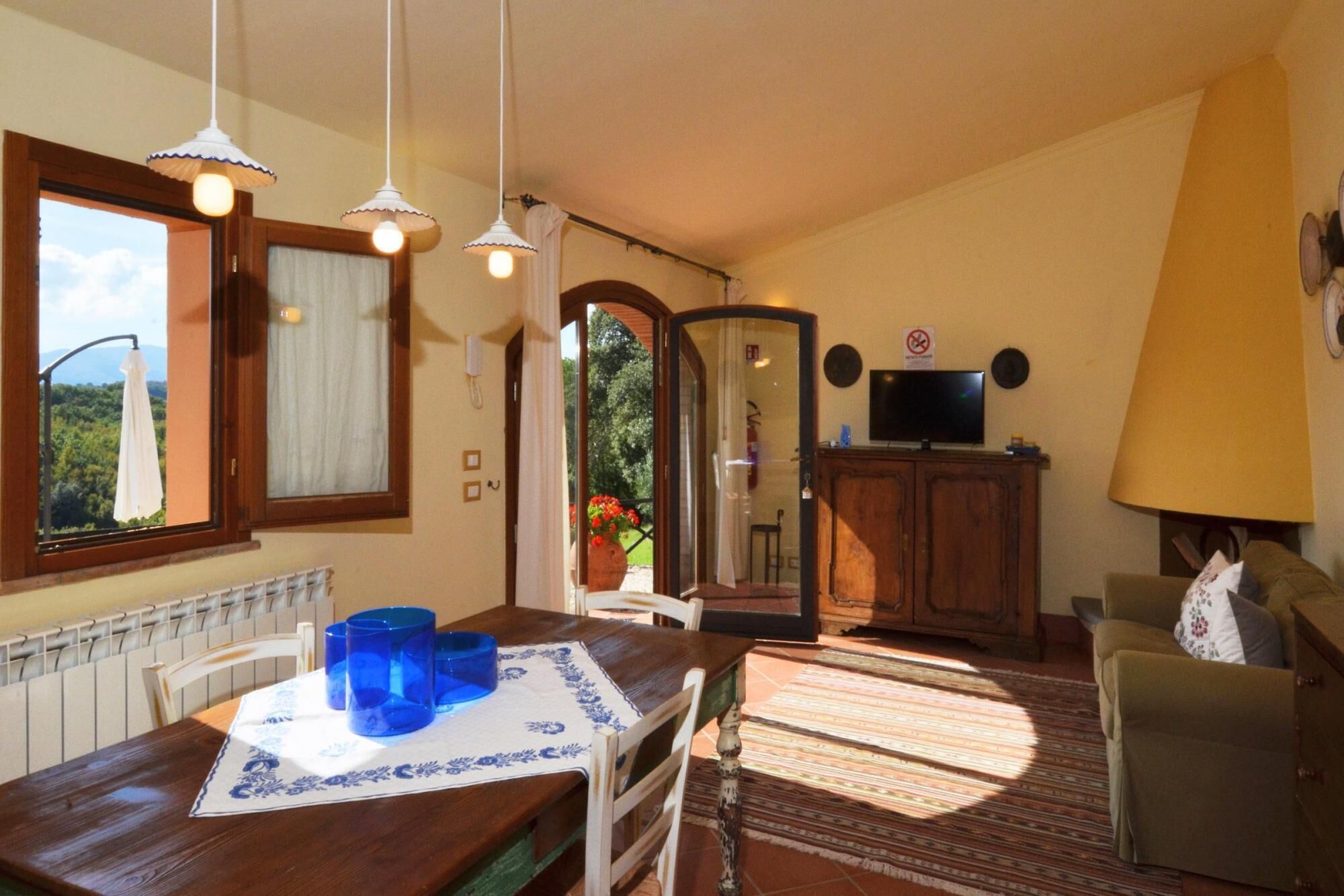 A dining area with a wooden table, blue glassware, and a view of greenery outside.