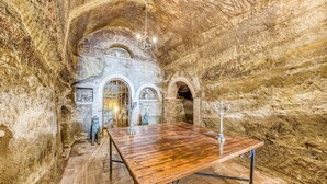 A spacious underground chamber with a wooden table, stone walls, and a chandelier. - Torre Del Melograno With Heated Pool (Castiglione in Teverina)