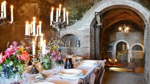 A dining area with a brick fireplace, candles, and a table set for a meal. - Torre Del Melograno With Heated Pool (Castiglione in Teverina)