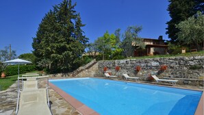 A swimming pool with lounge chairs and a stone wall.