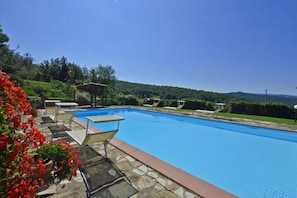 A swimming pool with lounge chairs and a pergola, surrounded by greenery and hills. - La Badia 1 in Tavarnelle Val di Pesa (Barberino Tavarnelle)