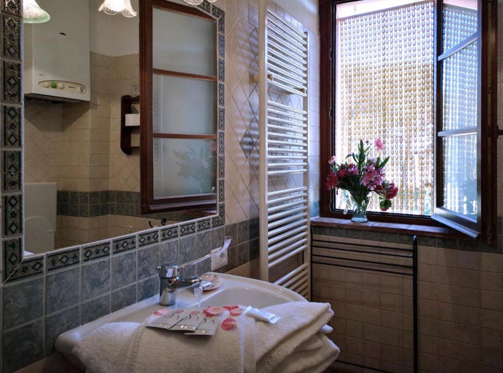 A bathroom with a sink, mirror, and window with a view.