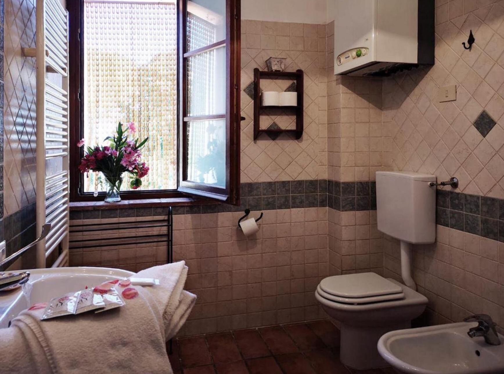 A bathroom with a toilet, bidet, and a window with a view of greenery.