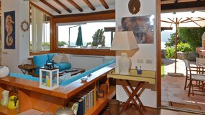 A cozy living room with a wooden bench, a sofa, and a table with books and decorative items. - Villa Ada in Ansedonia (Orbetello)