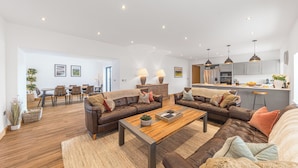 A spacious living area with leather sofas, a wooden coffee table, and a dining area with chairs and a table. - Old Stable (Ulverston)