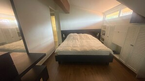 Een slaapkamer met een bed, bureau en een kledingkast.