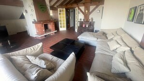 Een ruime woonkamer met een open haard, een bank en een salontafel.
