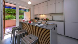 A modern kitchen with a central island, stainless steel appliances, and a view of greenery outside. - Coloratura in Paradiso Lugano (Paradiso)