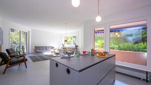 A modern kitchen with a central island, large windows, and a dining area with a sofa and table. - Coloratura in Paradiso Lugano (Paradiso)