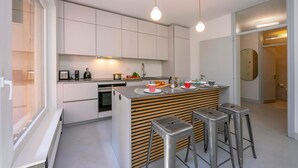 A modern kitchen with white cabinetry, a wooden island with stools, and pendant lighting. - Coloratura in Paradiso Lugano (Paradiso)
