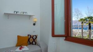 Une pièce avec un lit, une fenêtre à cadre rouge, une étagère fixée au mur sur laquelle est écrit le mot « rêve », et une vue sur les arbres et les montagnes à l’extérieur.