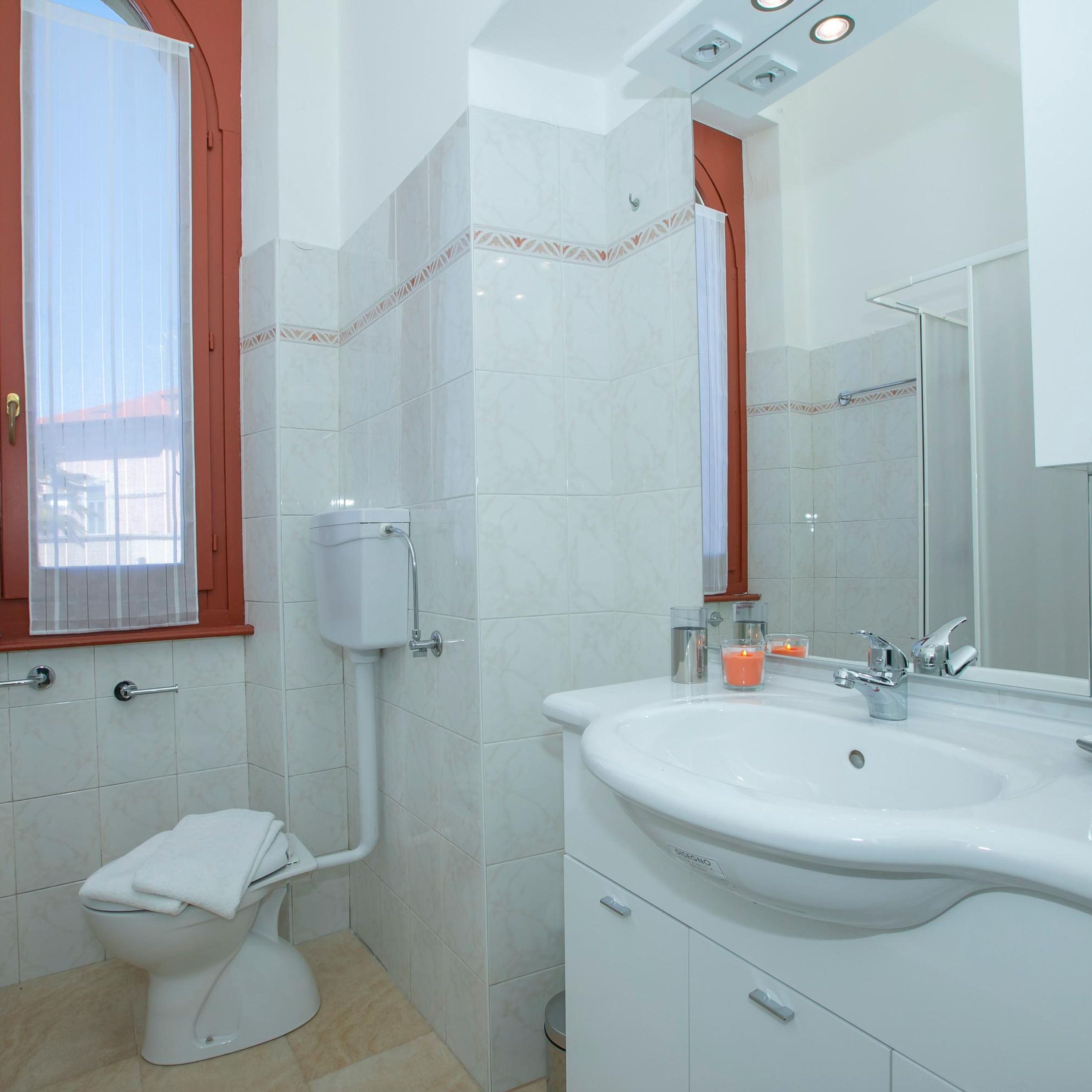 A bathroom with a toilet, sink, and mirror.