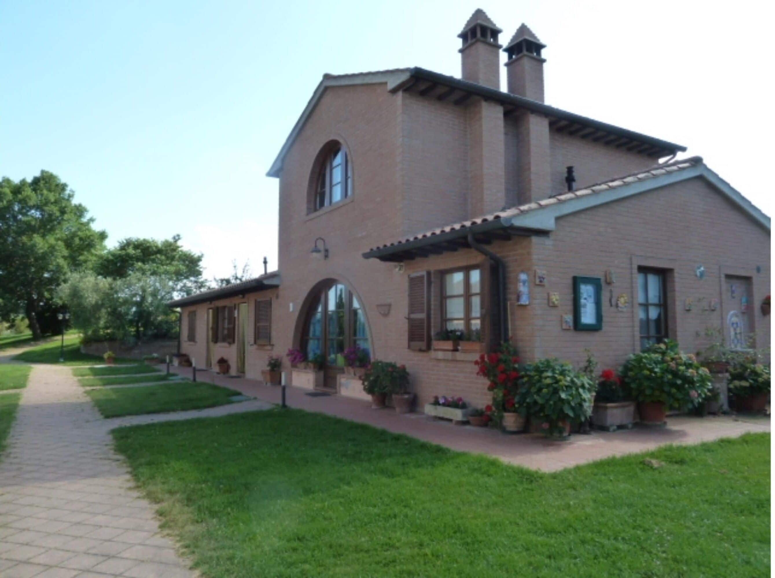 A two-story building with a brick facade, large arched windows, and a tiled roof.