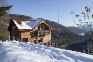 A wooden cabin with a sloped roof, surrounded by snow-covered hills and trees. - Pool Wellness Chalet Sunshine (Vransko)