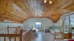 A spacious attic room with wooden beams, a bunk bed, a sofa, and a window with a view. - Pool Wellness Chalet Sunshine (Vransko)