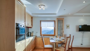 A modern kitchen with wooden cabinets, a built-in oven, and a dining area with a table and chairs. - Pool Wellness Chalet Sunshine (Vransko)