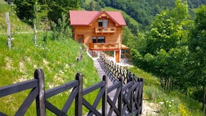 A wooden cabin with a red roof, a balcony, and a wooden deck leading to the entrance. - Pool Wellness Chalet Sunshine (Vransko)