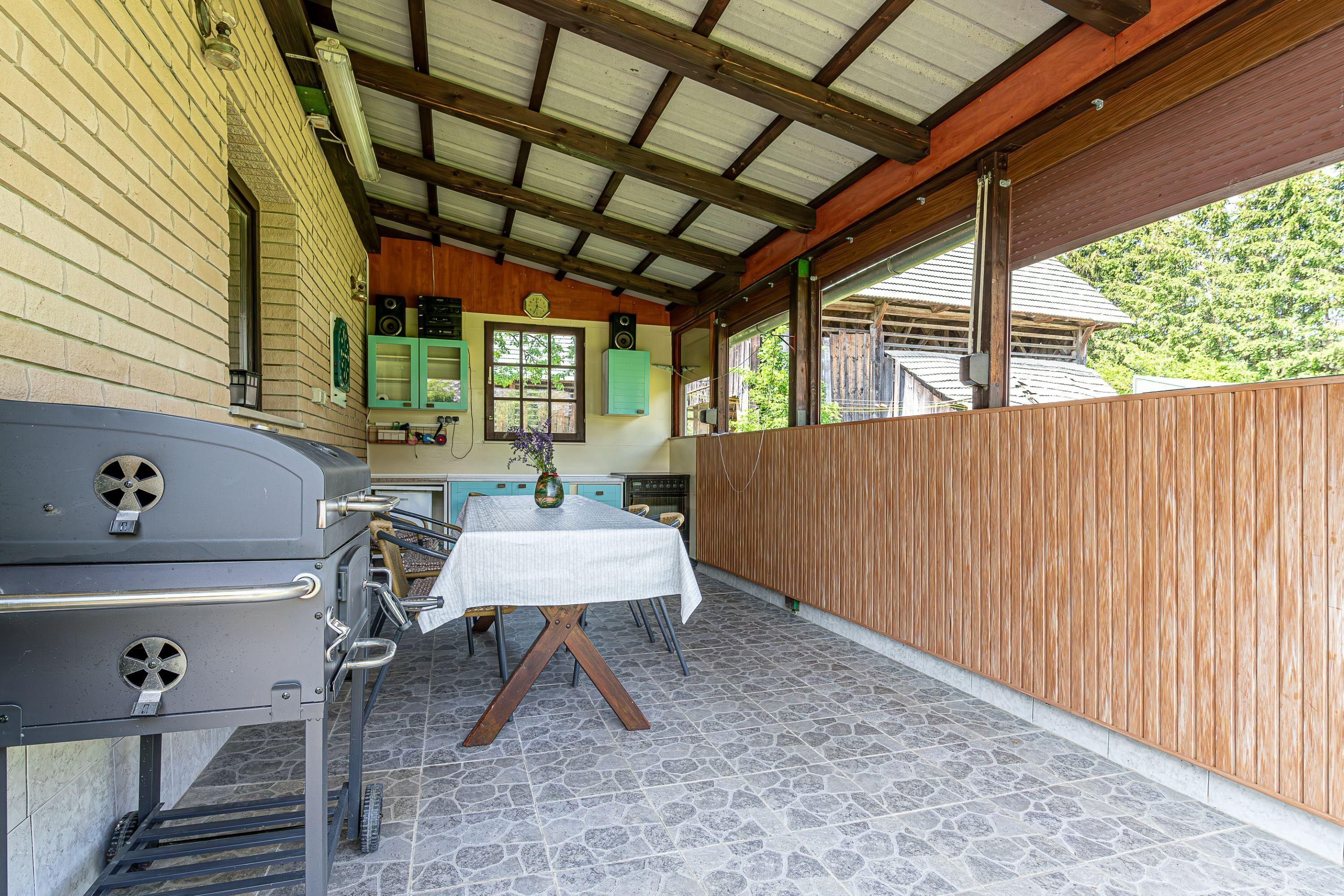 An outdoor patio with a grill, a table with chairs, and a wooden fence.