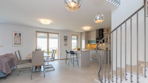 A modern apartment with a dining area, kitchen, and a staircase. - Panorama Seaview Kolomban (Koper)