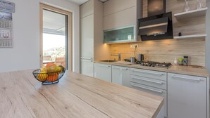 A modern kitchen with a wooden countertop, stainless steel appliances, and a view of the outdoors. - Panorama Seaview Kolomban (Koper)
