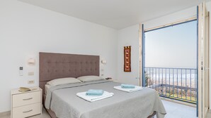 A bedroom with a bed, bedside table, and a view of the outside. - Panorama Seaview Kolomban (Koper)