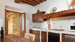 Eine Küche mit Holzschränken, einer Steinwand, einer gefliesten Rückwand und einer Holzbalkendecke.