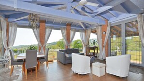 A spacious patio with wooden flooring, a dining area with chairs and a table, and a seating area with sofas and a small table. - Villa Borgiano in Scansano (Scansano)