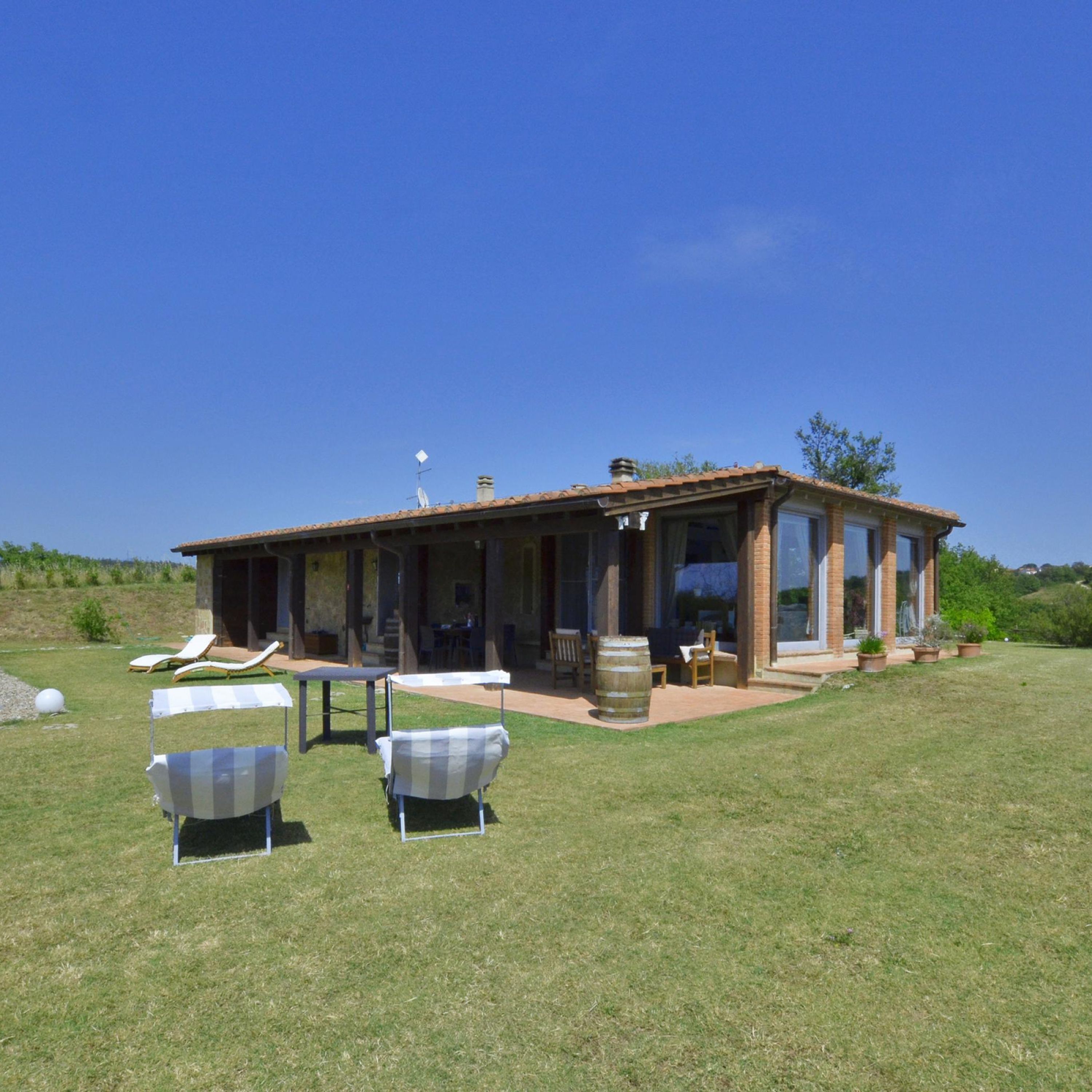 A house with a patio area, outdoor seating, and a large barrel.