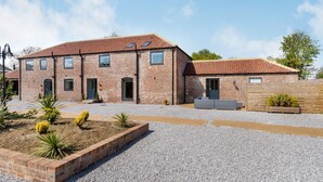 A two-story brick house with a tiled roof, a gravel driveway, and a small garden with plants. - Partridge Place (Hull)