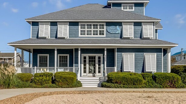 Une maison à deux étages avec un porche, une enseigne indiquant « Blue Heron » et une boîte aux lettres.