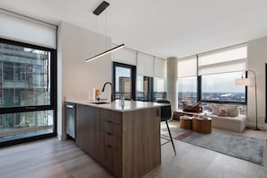 A modern kitchen with a central island, large windows, and a view of the city.