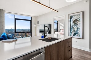 A modern kitchen with a large island, a built-in oven, and a view of the city.