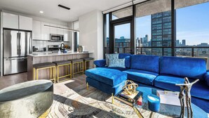 Un apartamento moderno con cocina, un sofá azul y vistas a la ciudad.