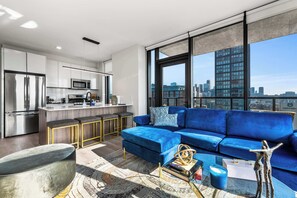 Un appartamento moderno con cucina, un divano blu e vista sulla città.