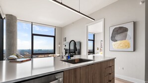 A modern kitchen with a large island, stainless steel appliances, and a view of the city. - City Views + Walk to Dining, Ideal for All (Chicago)