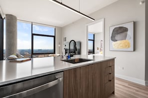 A modern kitchen with a large island, stainless steel appliances, and a view of the city. - City Views + Walk to Dining, Ideal for All (Chicago)