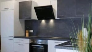 Eine moderne Küche mit weißen Schränken, einem eingebauten Ofen und einer schwarzen Arbeitsplatte.