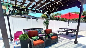 A covered patio with wicker furniture, a table, and chairs. - Busch Gardens Deluxe Edition w/heated pool (Tampa)
