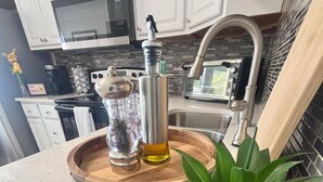 A kitchen with white cabinets, a stainless steel sink, a microwave, and a wooden countertop with a potted plant. - Busch Gardens Deluxe Edition w/heated pool (Tampa)