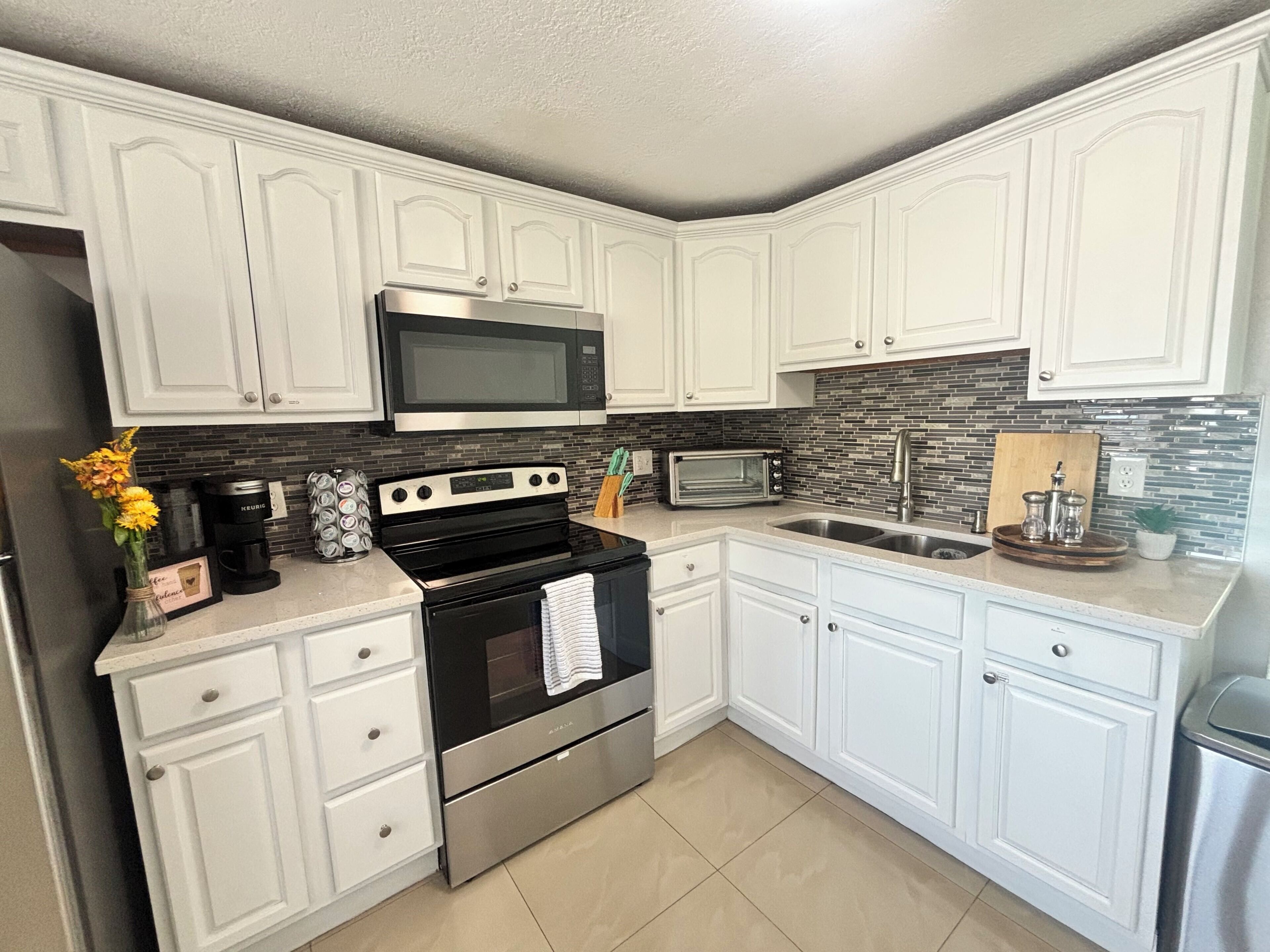 A modern kitchen with white cabinetry, a stainless steel stove, a microwave, and a toaster.