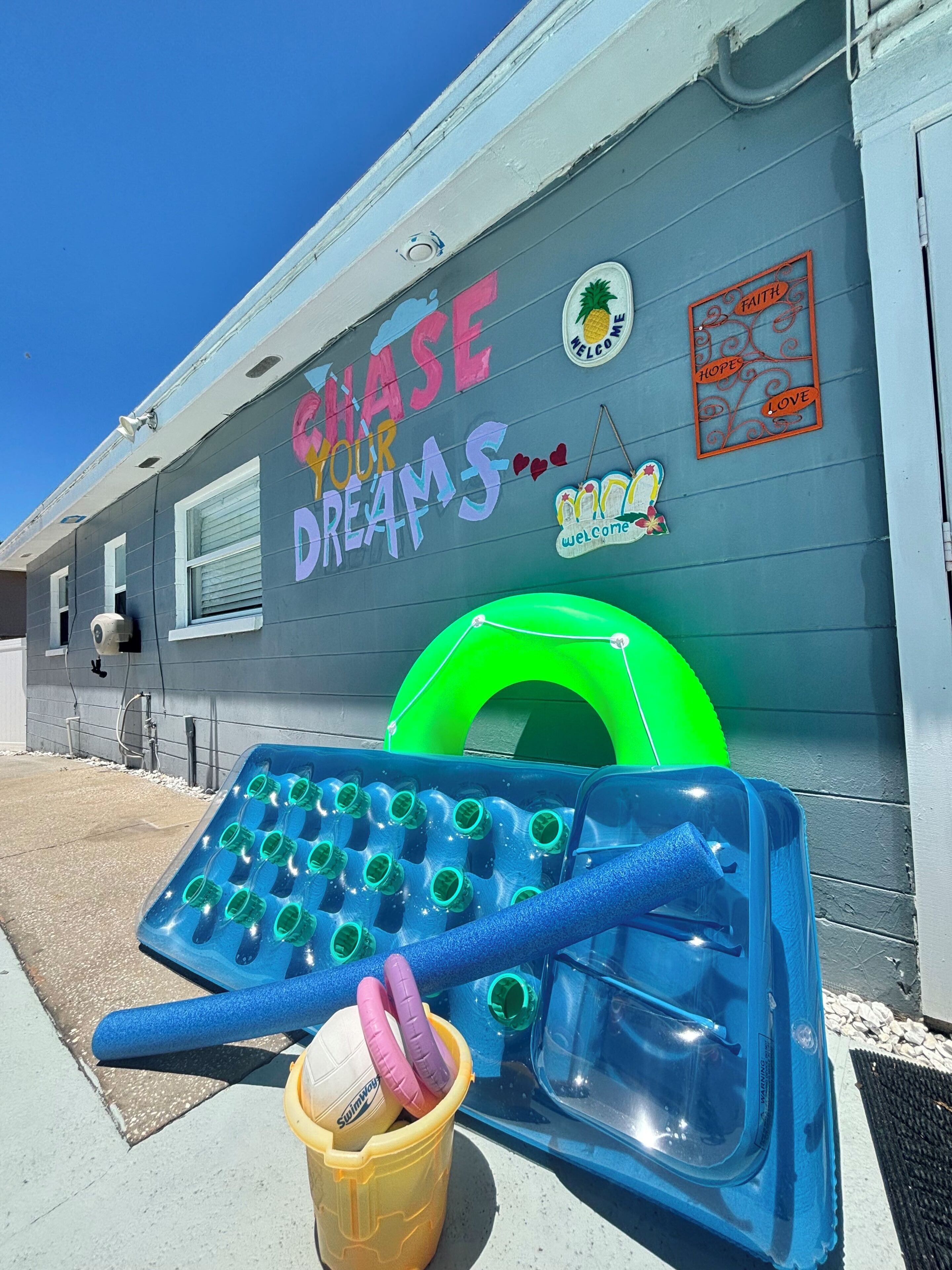 Ein Gebäude mit einem Schild, das 'CHASE YOUR DREAMS' zeigt, und einem grünen aufblasbaren Pool.
