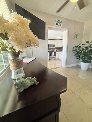 A kitchen area with white cabinets, a microwave, and a stove. There is a vase with white flowers on a counter.