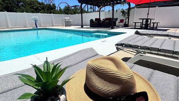 A poolside area with a lounge chair, a sun hat, and a pair of sunglasses. - Busch Gardens Deluxe Edition w/heated pool (Tampa)