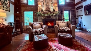 A cozy living room with a stone fireplace, leather armchairs, and a patterned rug. - Storybook Chalet/Watch Movies Under the Stars/NEW Hot Tub/Hiking/Biking/Concerts (Beech Mountain)
